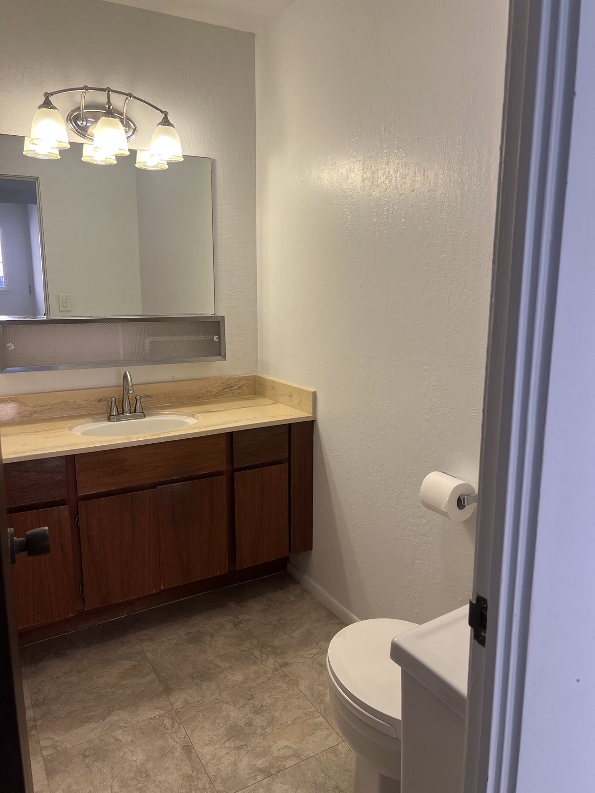 A bathroom with a toilet, sink, and mirror.